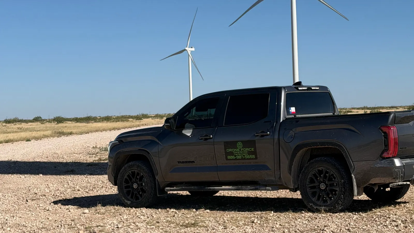 Drone Force branded truck at a wind farm under a blue sky