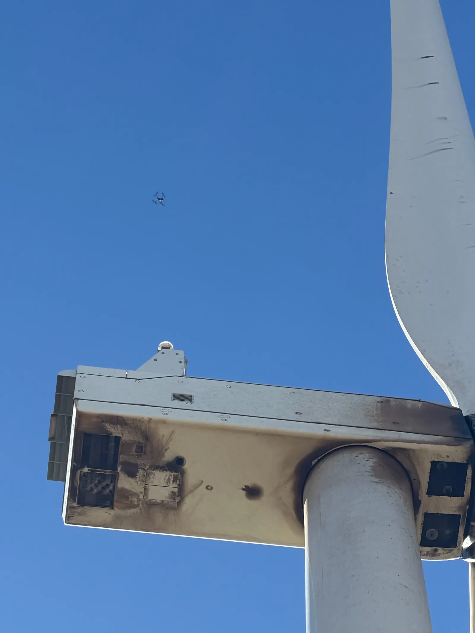 Inspection drone inspecting a wind turbine blade with visible leading-edge erosion