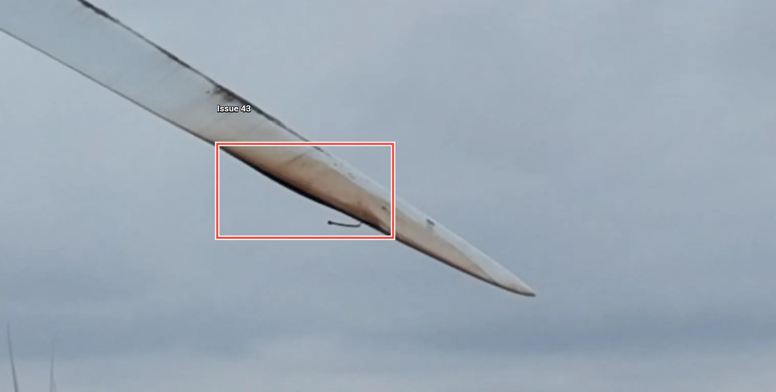 Drone close-up of a wind turbine blade tip with a bondline defect boxed for review